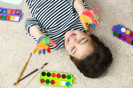 Boy with painted hands lying on carpet